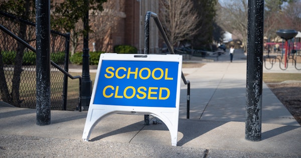 Image shows a sign reading "School Closed" is positioned outside a school. Photo credit: Ayman Haykal.