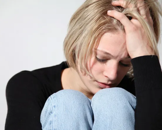 A woman looking down with her hand on her head