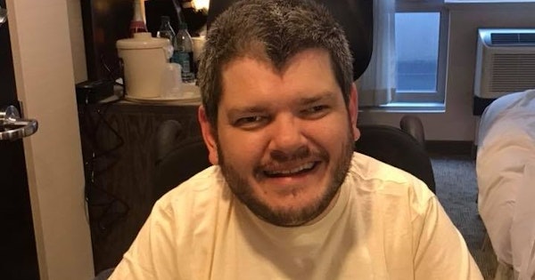 Todd has short hair and a beard. He's wearing a t-shirt with an image of American President Franklin D Roosevelt. The words 'For a new deal' surround the image. Todd is a wheelchair user.