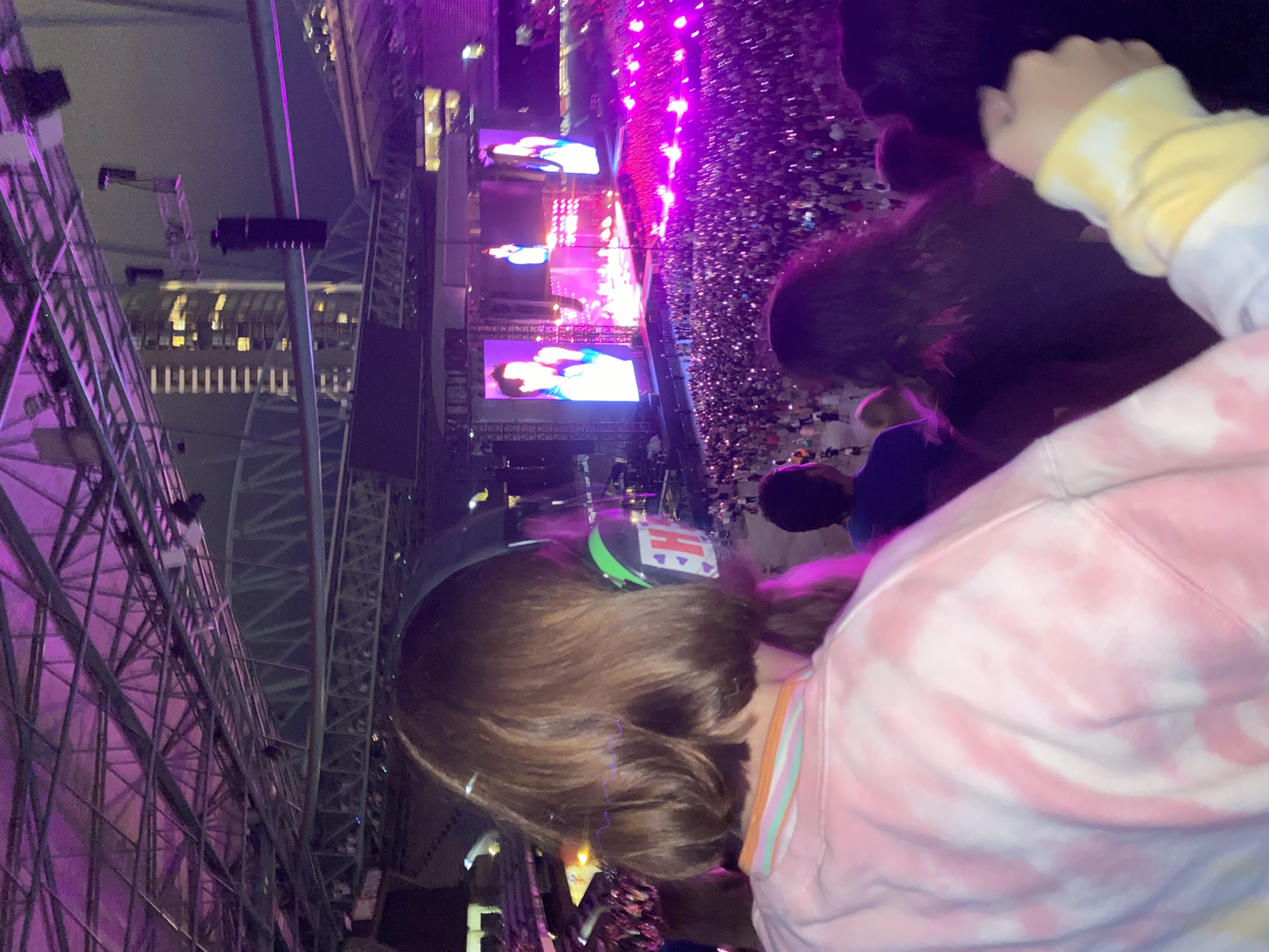 A teenager wearing noise-cancelling headphones and a colourful jumper rocks out at a music concert.