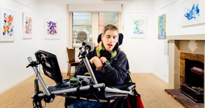 Artist Oliver Mills is in an exhibition room surrounded by his art