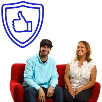 Two people are sitting on a couch smiling. There is a safety icon above them.