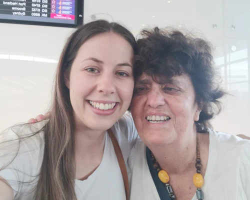 Tabitha and Gisele are embracing each other and smiling. Both are wearing white t-shirts. They are pictured in the Perth Airport.