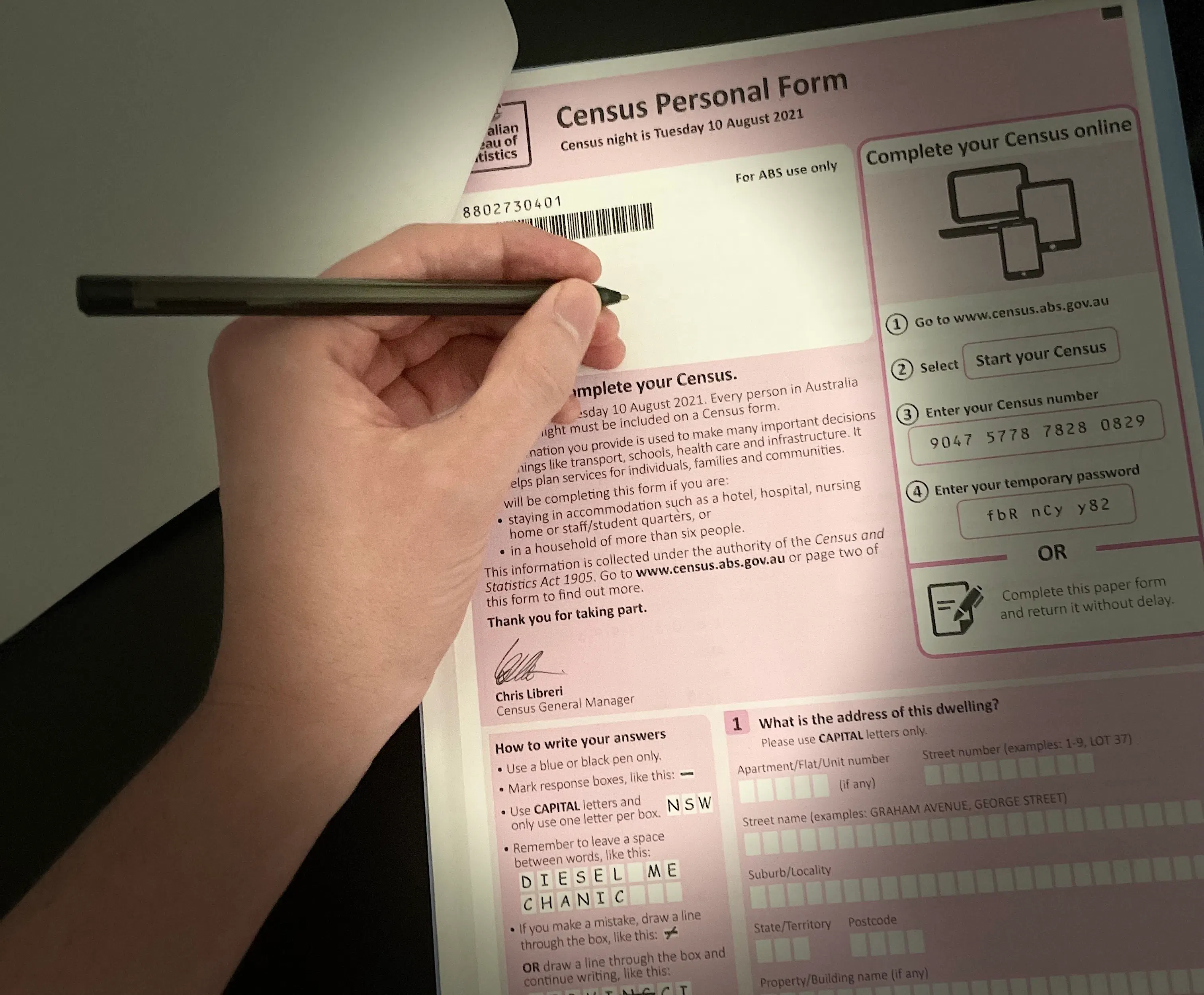 A hand that's holding a pen is hovering over the census form.