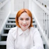 Elly Desmarchelier is smiling, wearing a white outfit with orange hair
