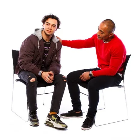 A man supporting antoher man, withhis hands on his shoulder