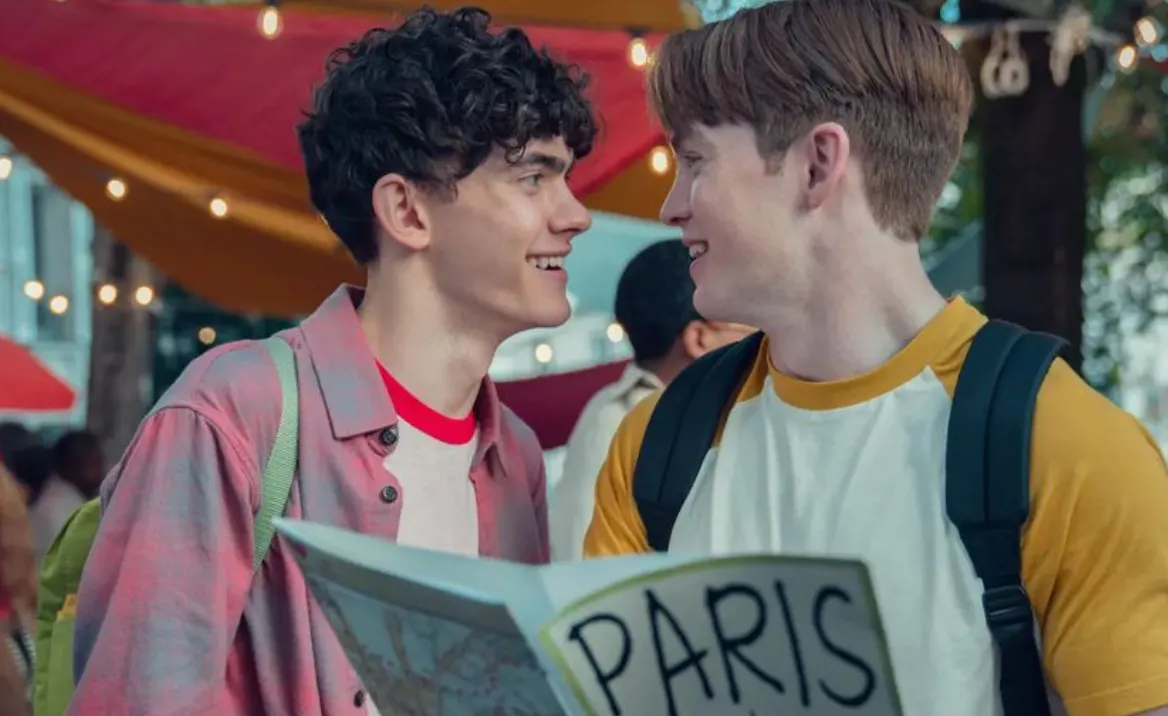 Two young men wearing backpacks smile at each other. One of them is holding a map with the title 'Paris'.