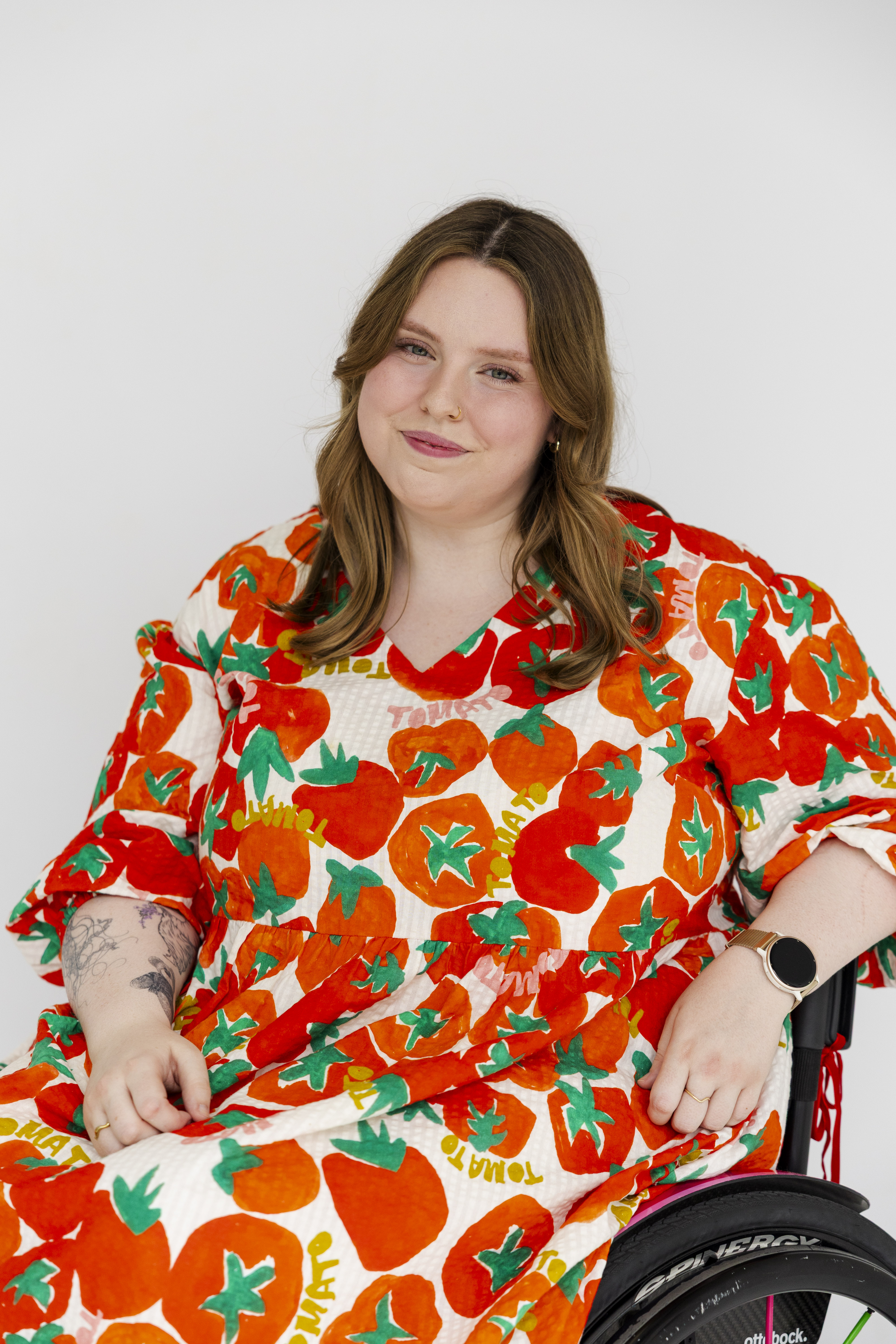 Jasmin Scriven, a disability advocate and content creator, has shoulder-length brown hair and wears a long tomato-print dress. Jasmin is a wheelchair user.&nbsp;