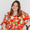Jasmin Scriven, a disability advocate and content creator, has shoulder-length brown hair and wears a long tomato-print dress. Jasmin is a wheelchair user.