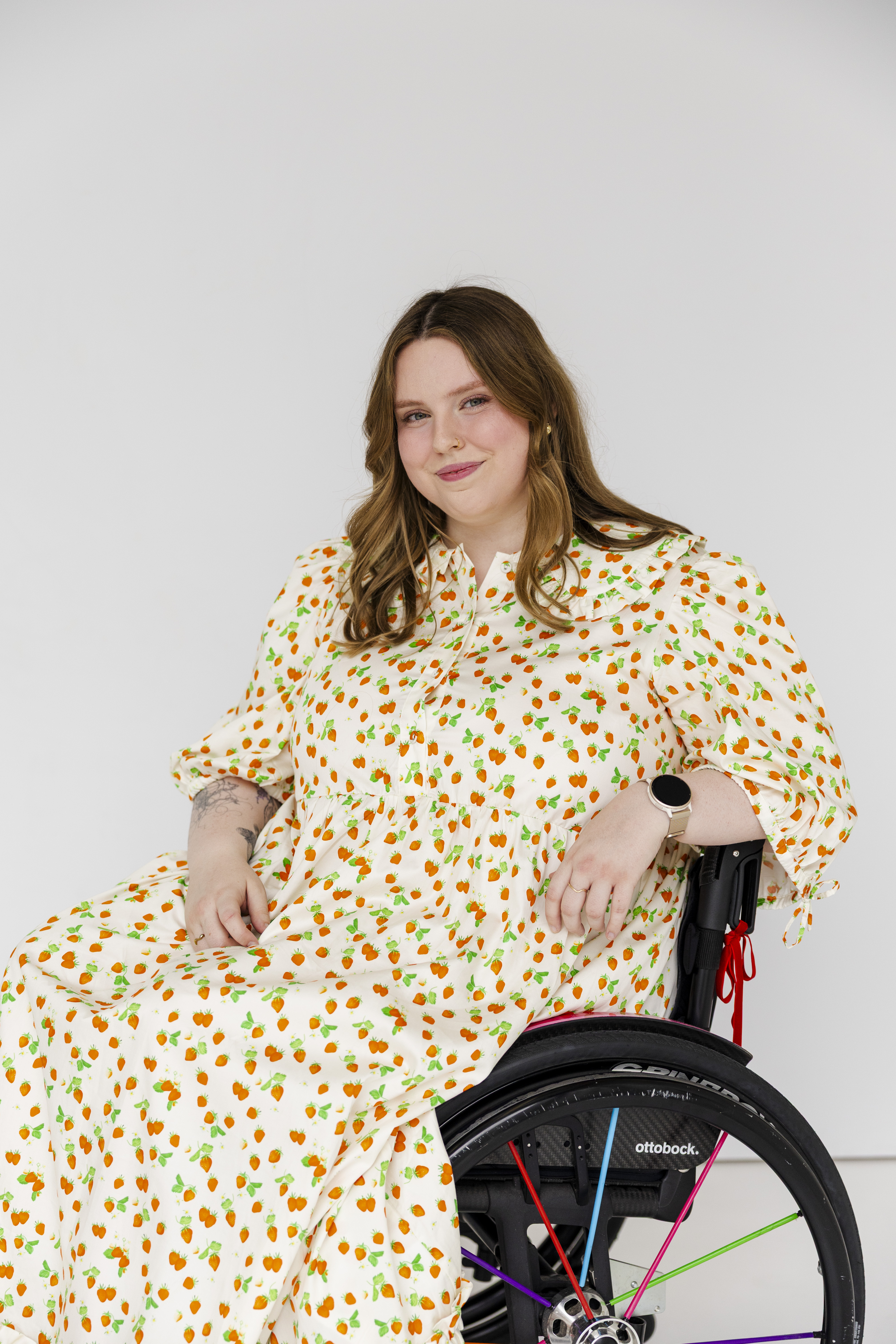 Jasmin Scriven, a disability advocate and content creator, has shoulder-length brown hair and wears a long strawberry-print dress. Jasmin is a wheelchair user.&nbsp;