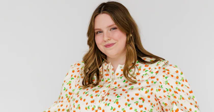 Jasmin Scriven, a disability advocate and content creator, has shoulder-length brown hair and wears a long strawberry-print dress. Jasmin is a wheelchair user.