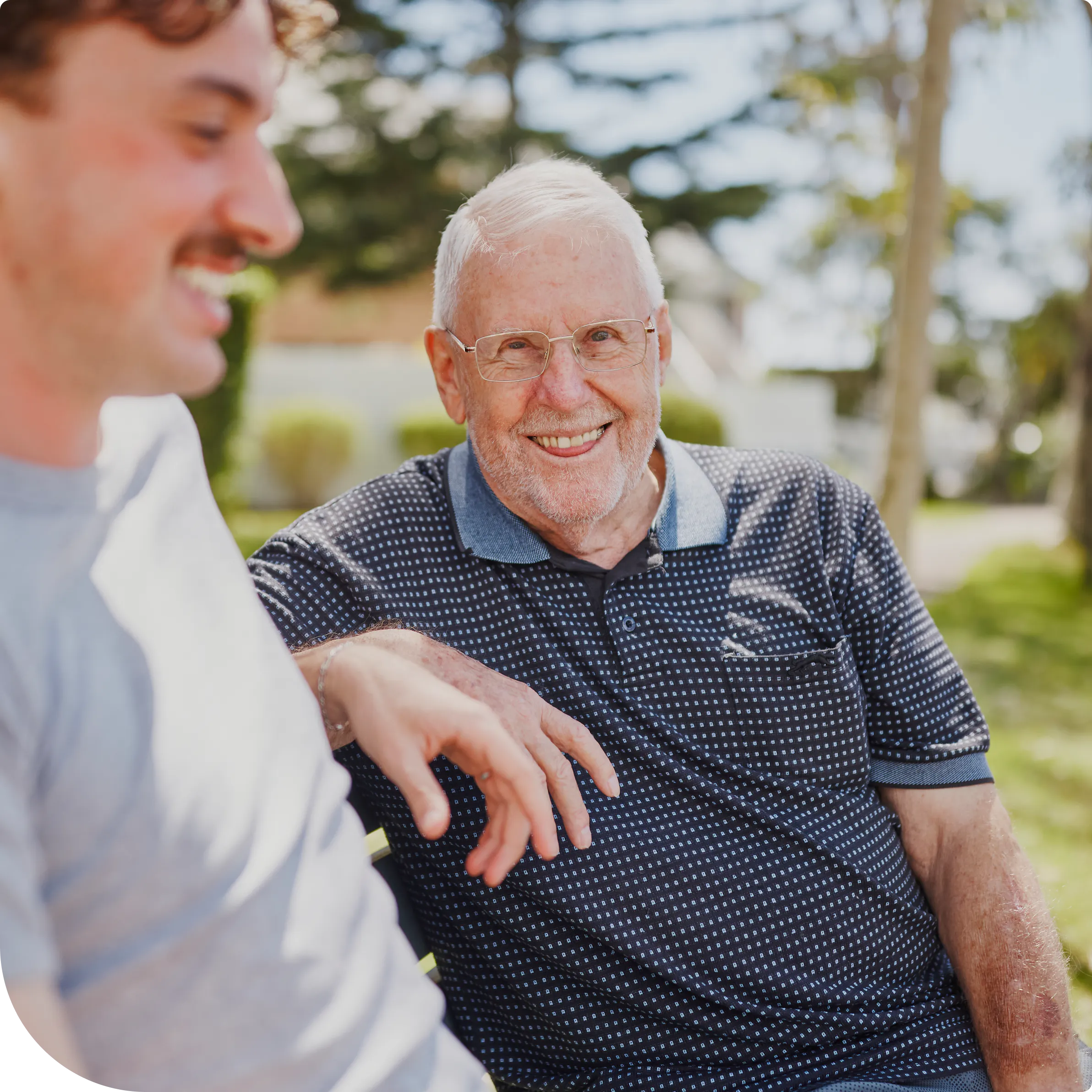 Hireup client Frank chats with his support worker Luka on a park bench.