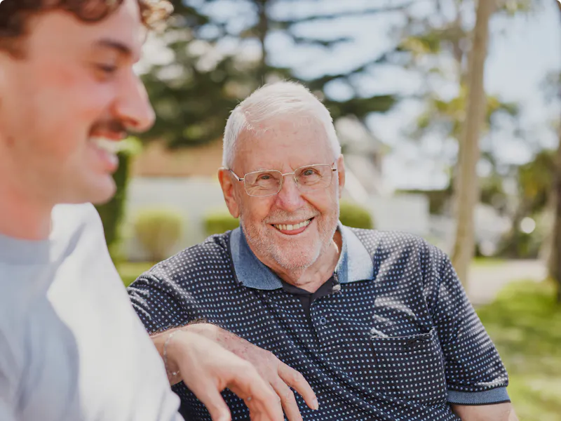 Hireup client Frank chats with his support worker Luka on a park bench.