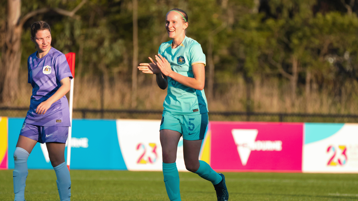 Athlete, Tamsin, is clapping in celebration on a soccer field. Tamsin wears her soccer uniform.