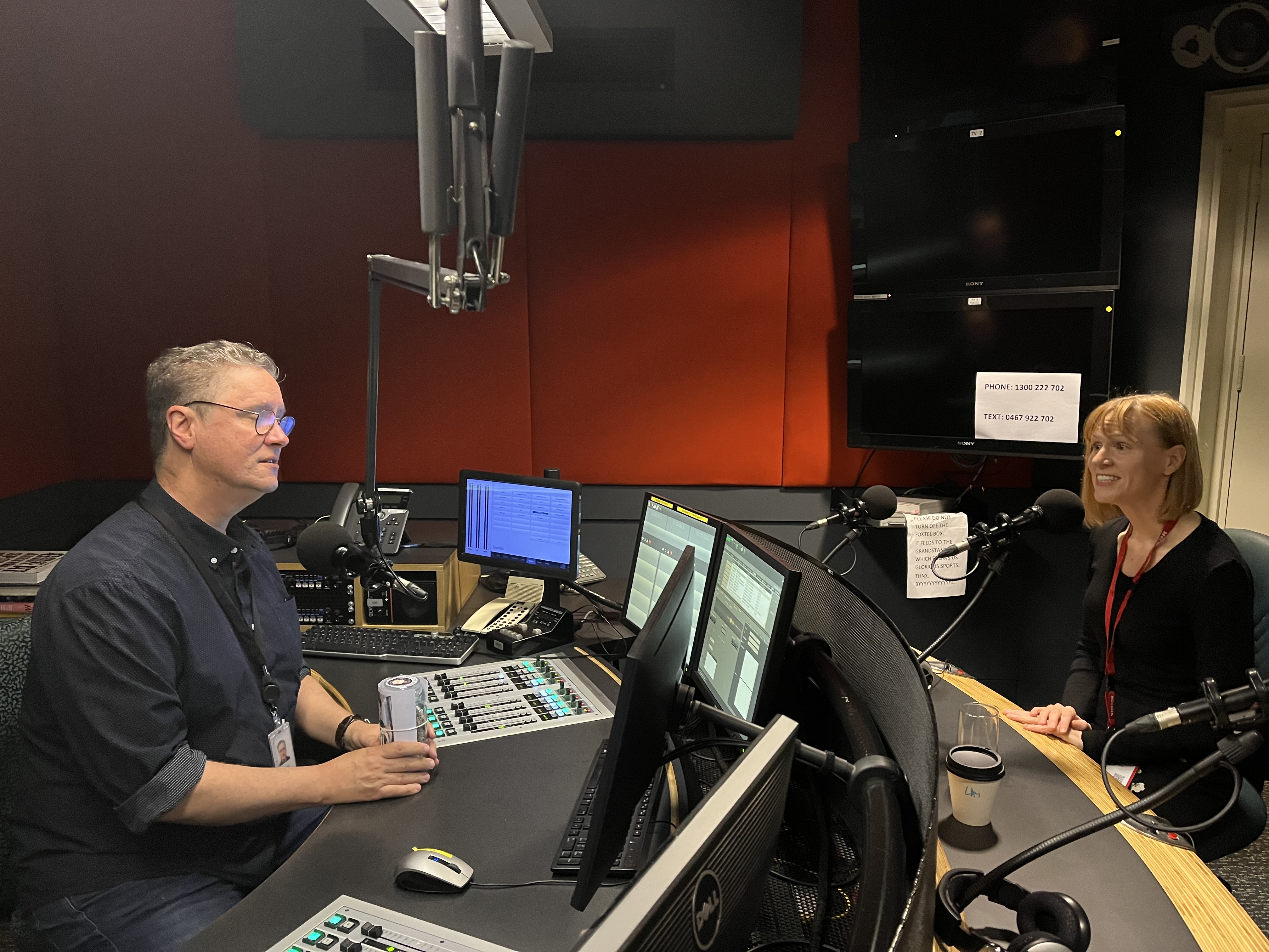 Image show Briana Blackett in an ABC radio studio with host, Richard Fidler. Both are seated opposite each other, speaking into microphones. 