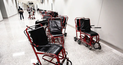 A cluster of worn-out transit wheelchairs stranded messily in an airport hallway.