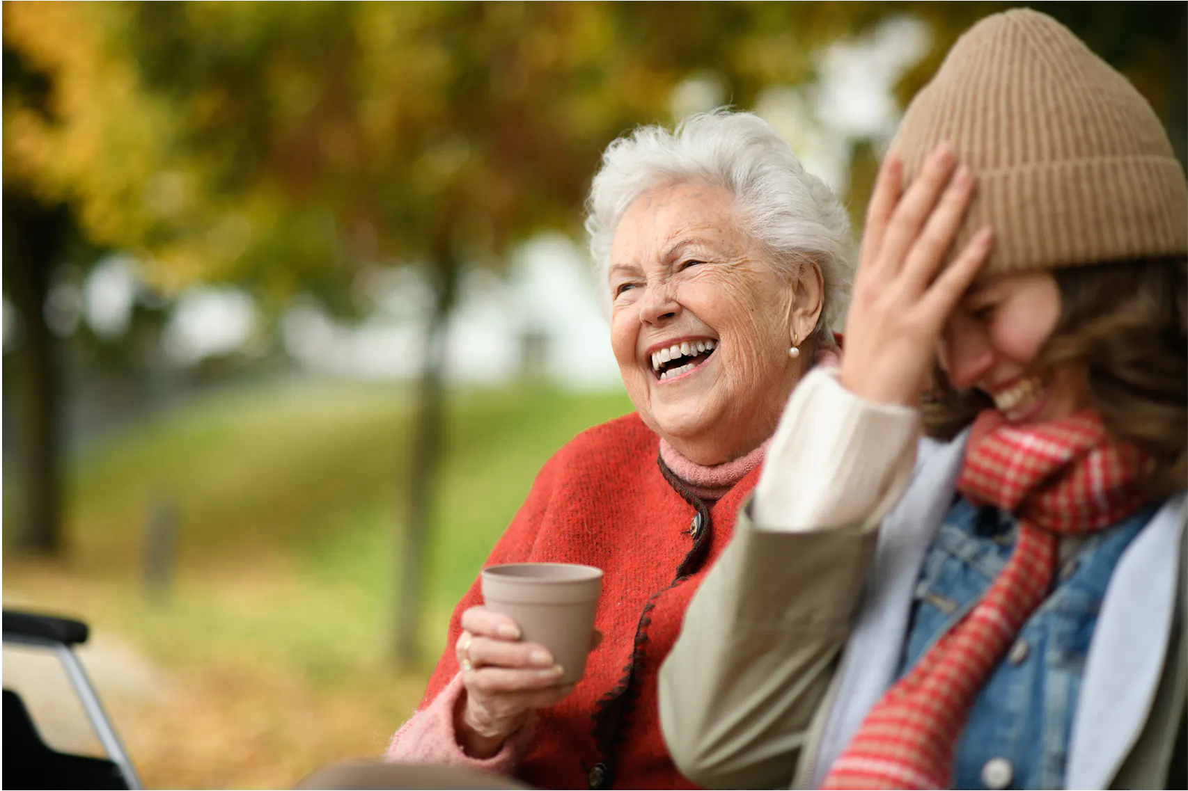 A client laughing with their support worker in a park. 