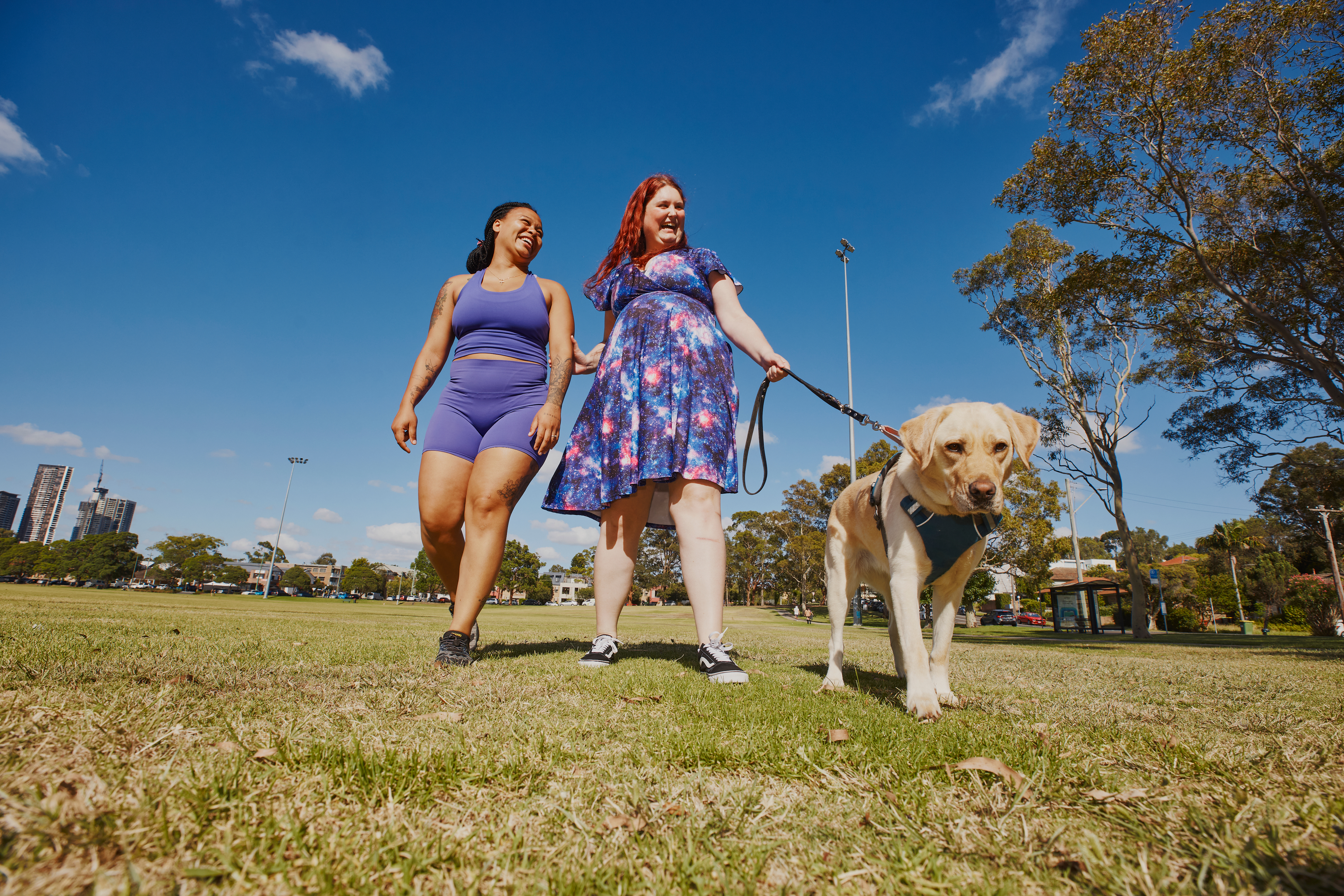 Hireup client and worker Kirsten and Paulla on a walk with a guide dog in a park.