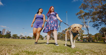 Hireup client and worker Kirsten and Paulla on a walk with a guide dog in a park.