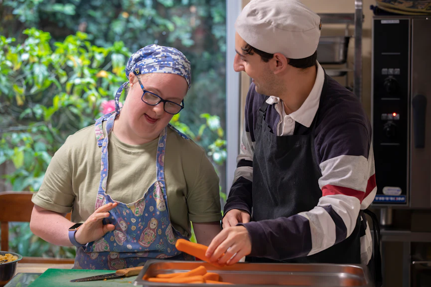 Hireup client Amy works in a kitchen with her worker Zak.