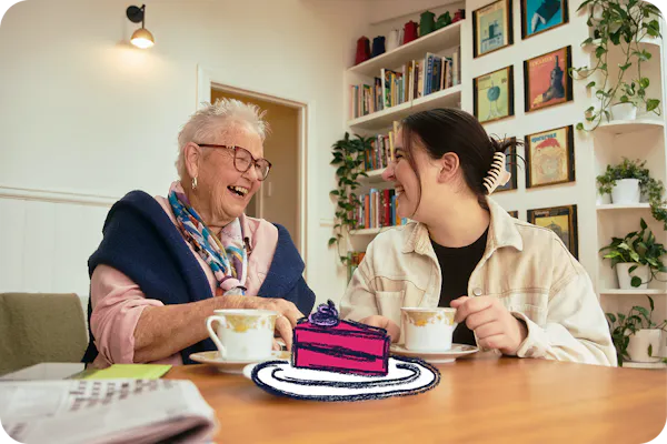 Hireup client Elsie and support worker Emma having tea and cake together.
