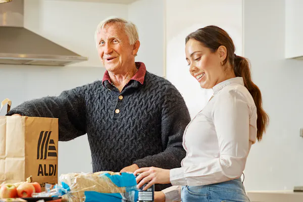 Hireup support worker Brenda helps client Dirk unpack his groceries.