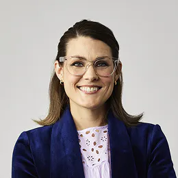 A smiling headshot of Alexis Copp. She wears glasses and has shoulder length brown hair.