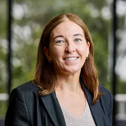 A smiling headshot of Emma White. She has long, light brown hair and wears a black blazer over a cream top.