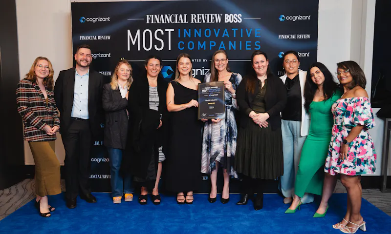 A group of ten Hireup team members are at the Australian Financial Review Boss Awards night. They're gathered in front of a media wall that has the AFR logo, and two of them are holding a large certificate.