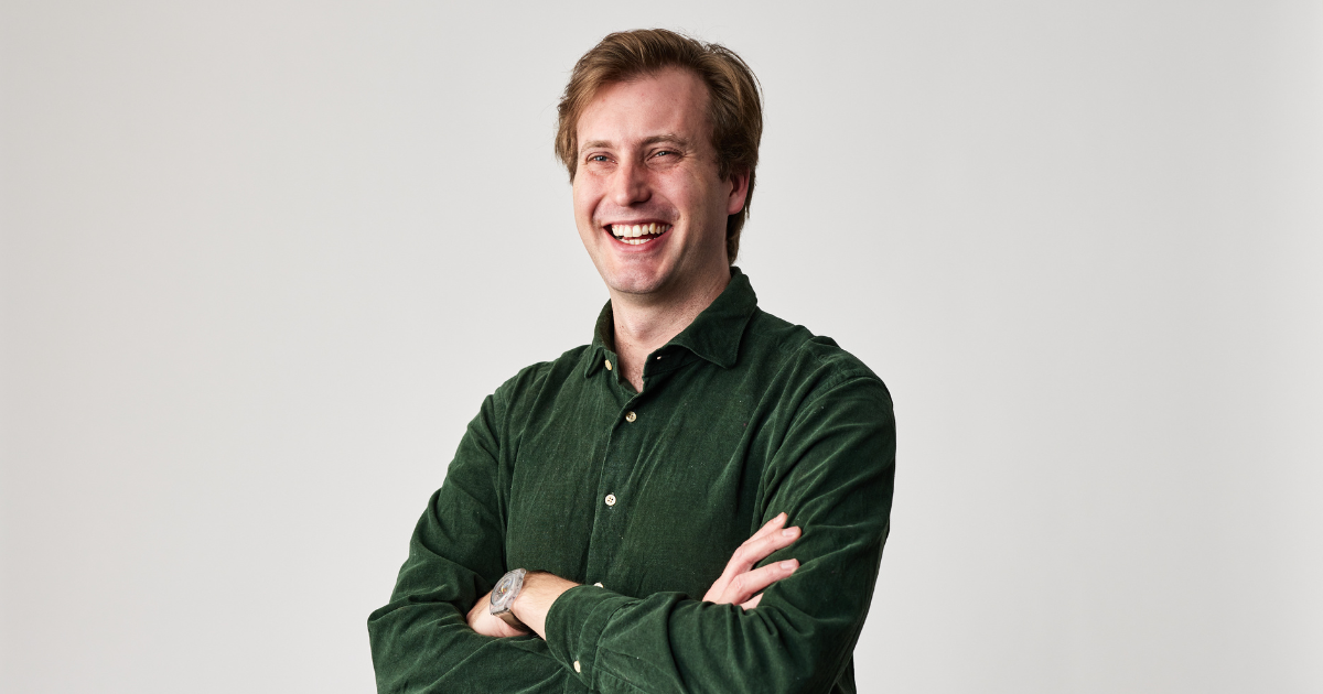 Peter Willis, Hireup's CEO, has short, brown hair and is wearing a dark, green corduroy shirt. He's smiling, with his arms folded, in front of a white wall.