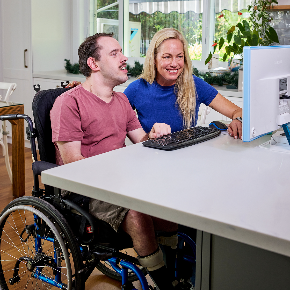Hireup client Daniel uses the computer with assistance from his support worker Miriam.