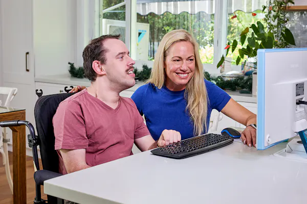 Hireup client Daniel uses the computer with assistance from his support worker Miriam.