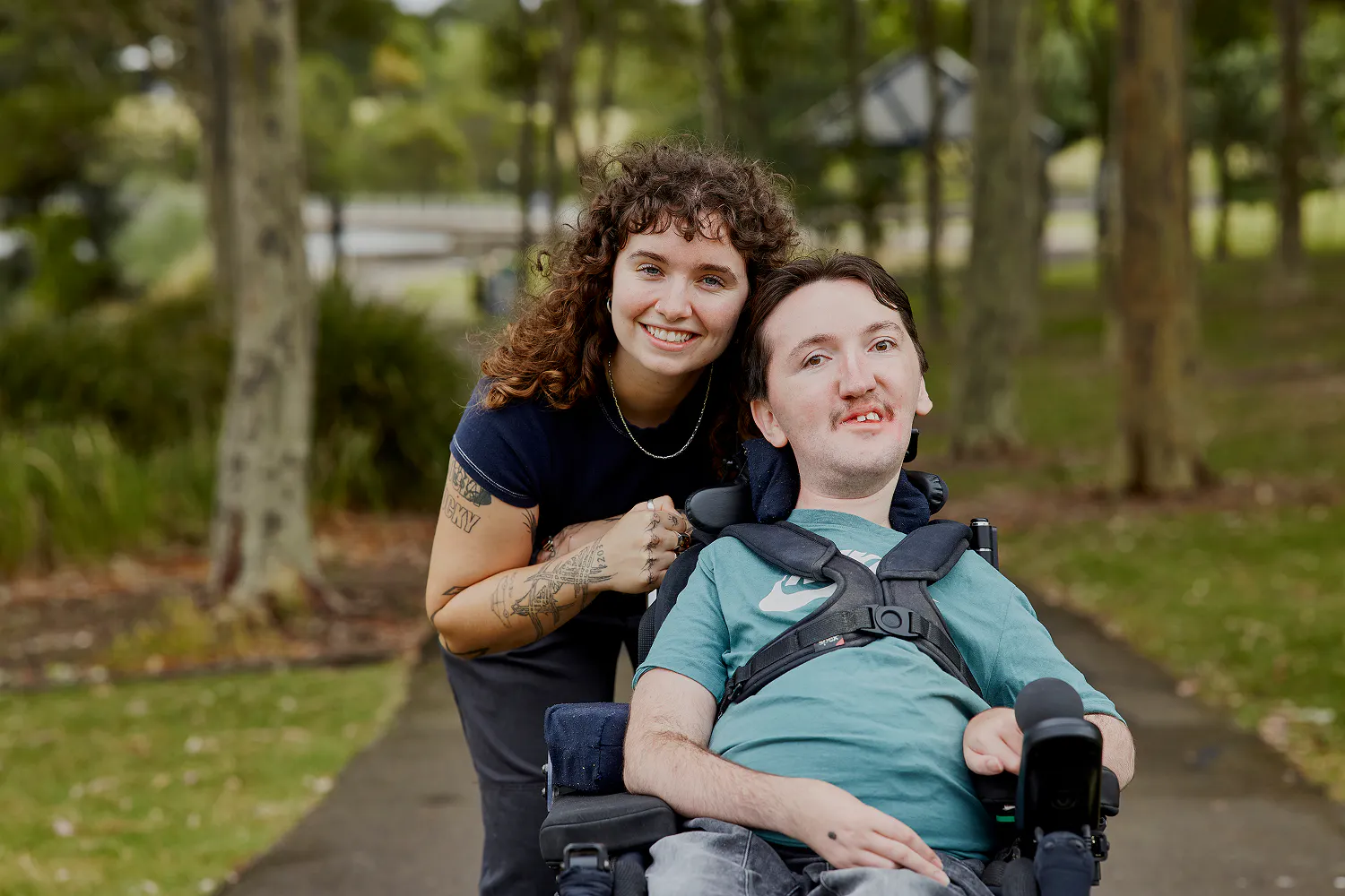 Hireup client Tom smiles at the camera with support worker Sarah.