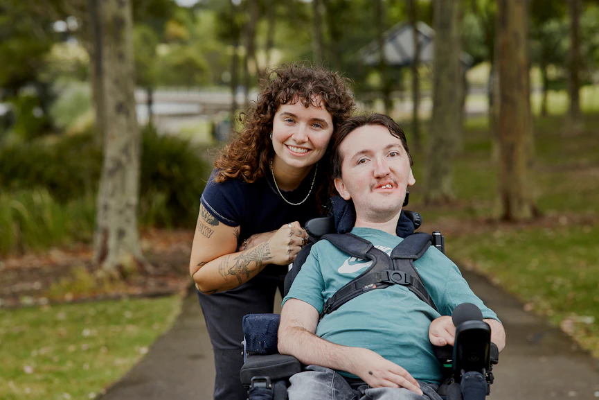 Hireup client Tom smiles at the camera with support worker Sarah.