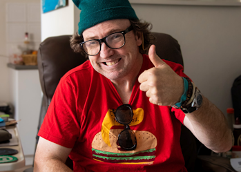 A Hireup user smiles at the camera with thumbs up.