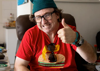 A Hireup user smiles at the camera with thumbs up.
