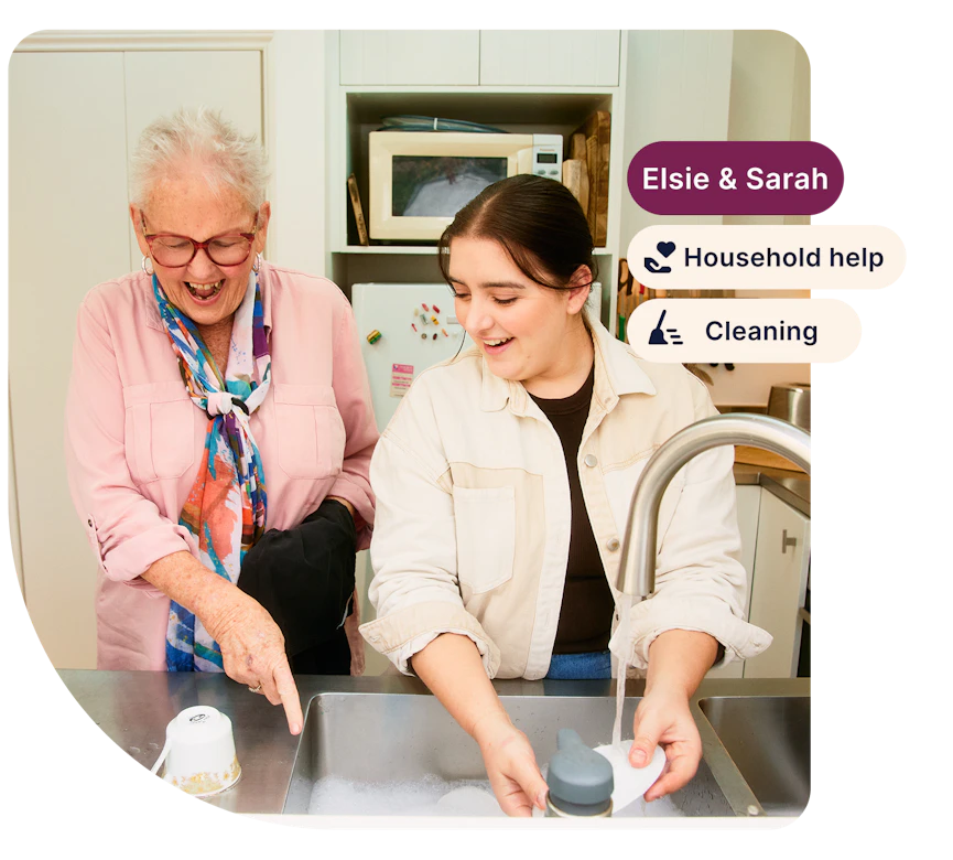 Support worker Sarah helps aged care client Elsie with the dishes. There are three tags on the right side: "Elsie and Sarah", "Household help" and "Cleaning".