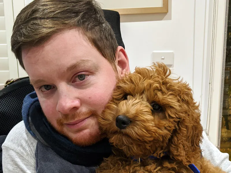 Carl Thompson snuggles with his dog, Oscar, while sitting in his wheelchair.