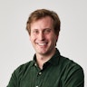 Peter Willis, Hireup's CEO, has short, brown hair and is wearing a dark, green corduroy shirt. He's smiling, with his arms folded, in front of a white wall.