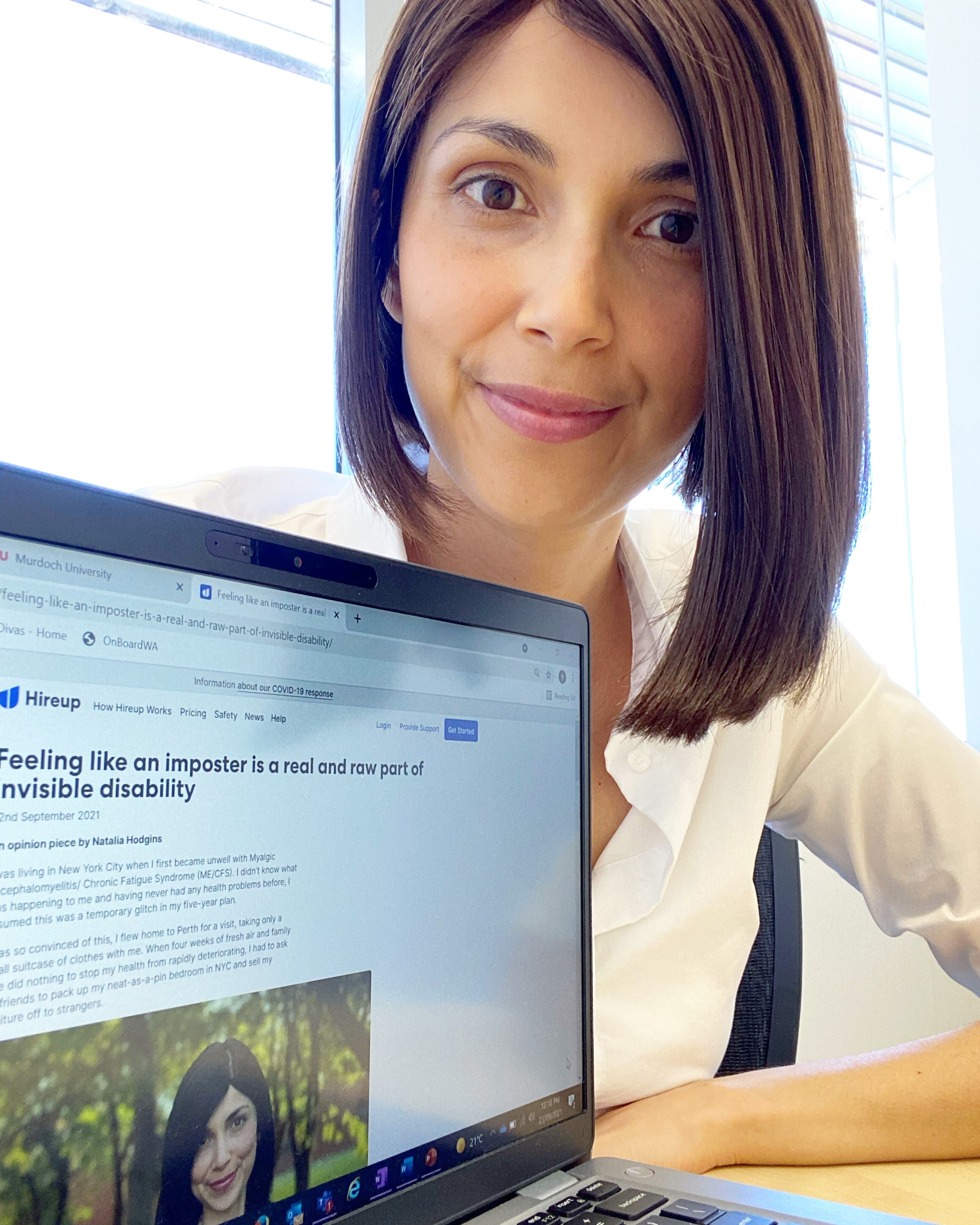 Natalia is a young woman with short, dark hair. She is leaning over a laptop that has a photo of her on screen. Natalia is smiling.