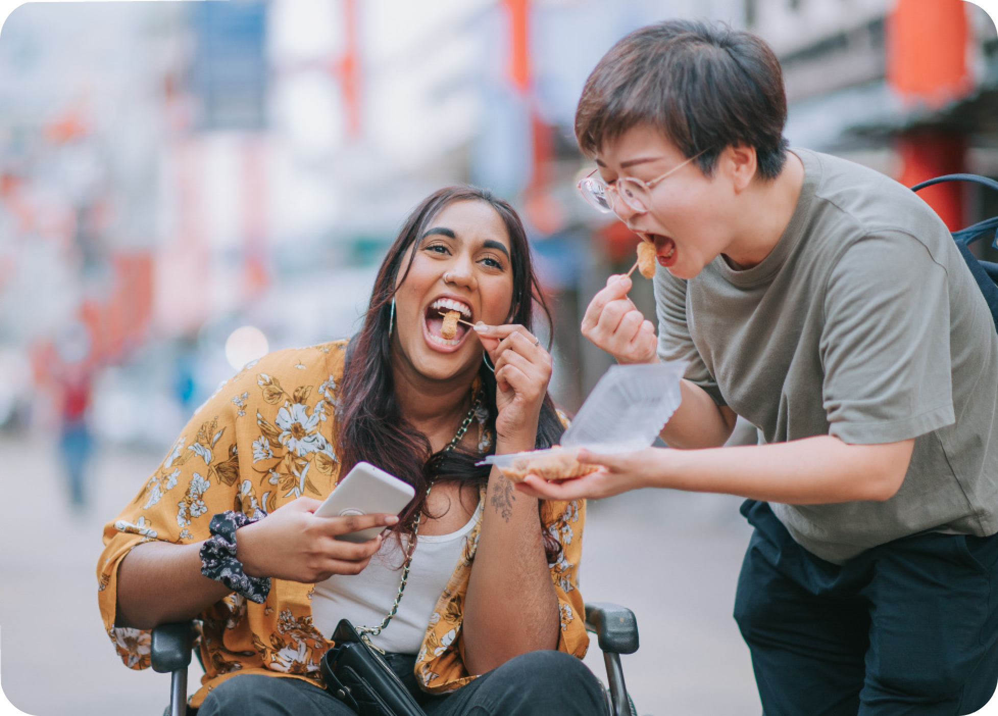 A person in a wheelchair enjoys a snack with their support worker.
