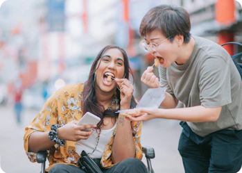 A person in a wheelchair enjoys a snack with their support worker.