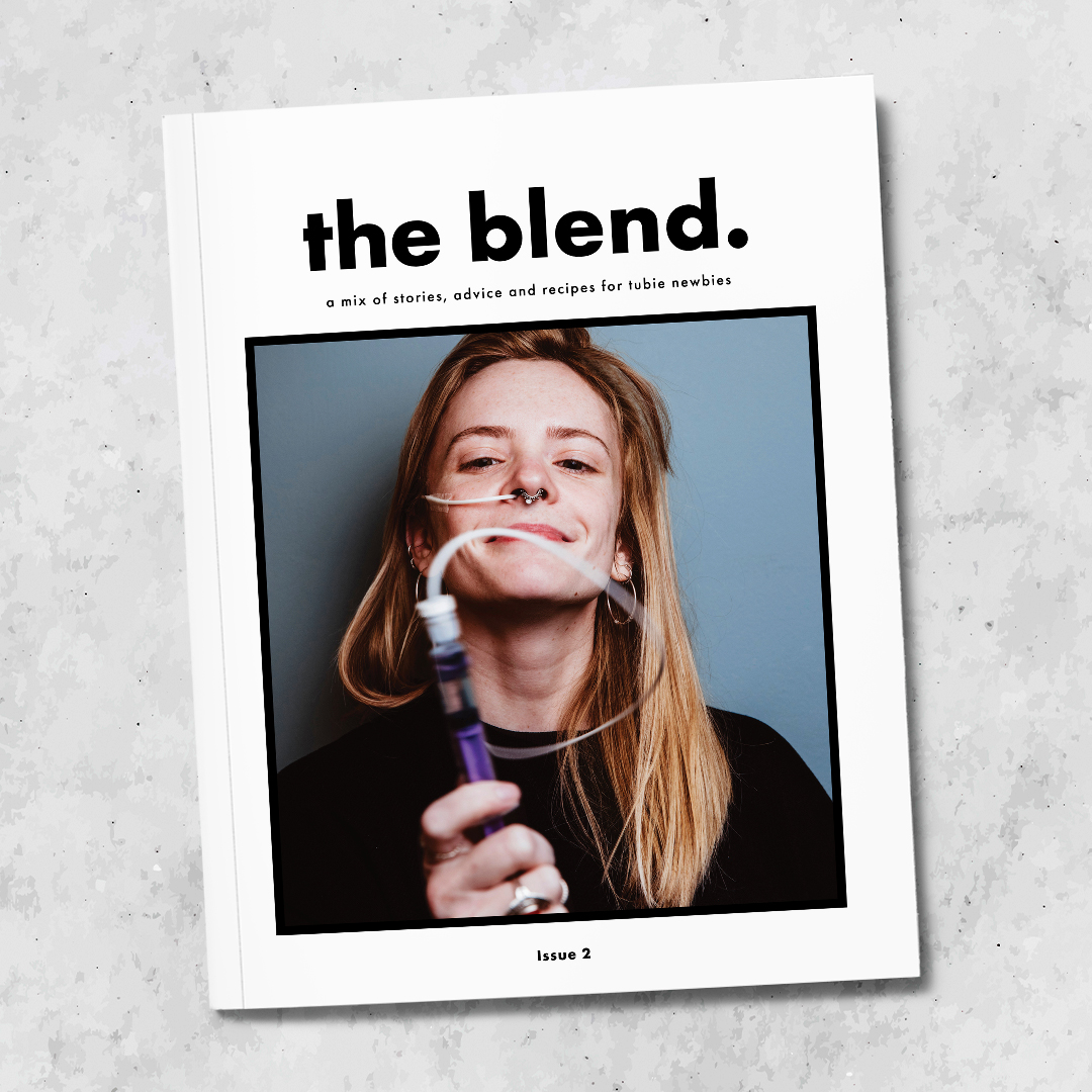 A magazine sits on a marble background. It's called The Blend: a mix of stories, advice and recipes for tubie newbies. It features cover star Loretta Harmes, The Nil By Mouth Foodie, who has an NG tube.