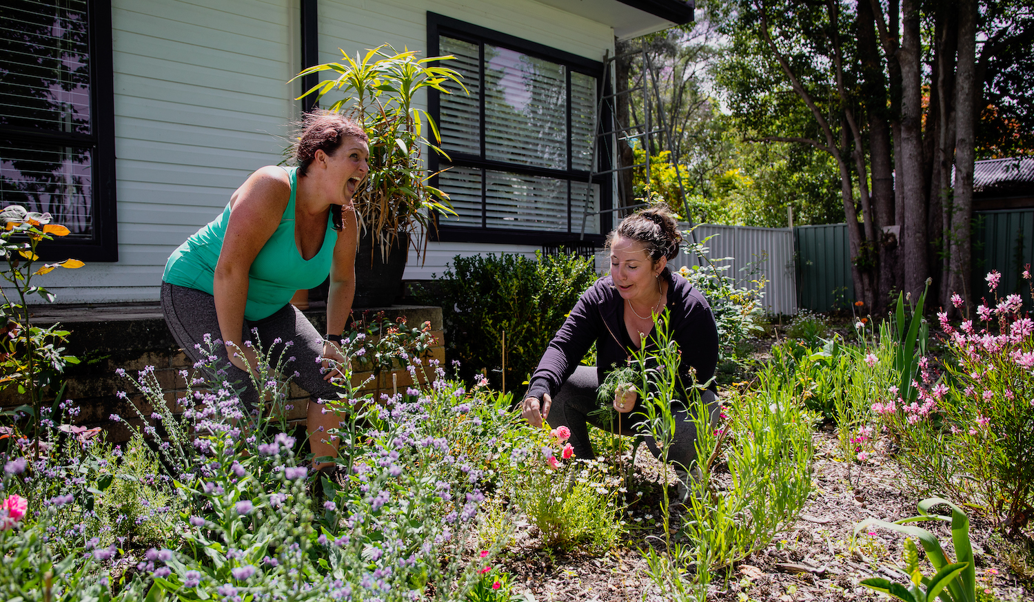 Sam and Portia are laughing amongst flowers in Portia's front yard