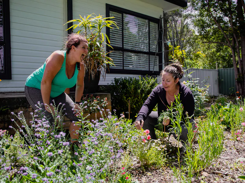 Sam and Portia are laughing amongst flowers in Portia's front yard