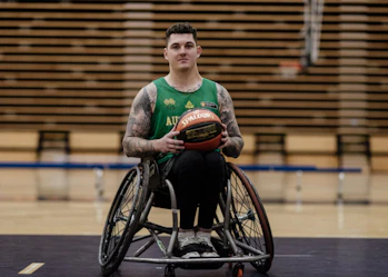 Australian wheelchair basketball player Jeremy Tyndall is on a basketball court. He's holding a basketball and looking at the camera.