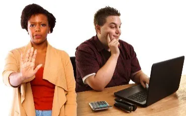A woman holding out her hand to say stop. Behind her a man uses a computer.