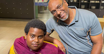 William Tatipata, co-founder and owner of XtremeCARE Australia, sits with Charlie Kris, an NDIS participant, on Thursday Island, Torres Strait.