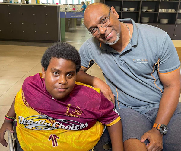 William Tatipata, co-founder and owner of XtremeCARE Australia, sits with Charlie Kris, an NDIS participant, on Thursday Island, Torres Strait.
