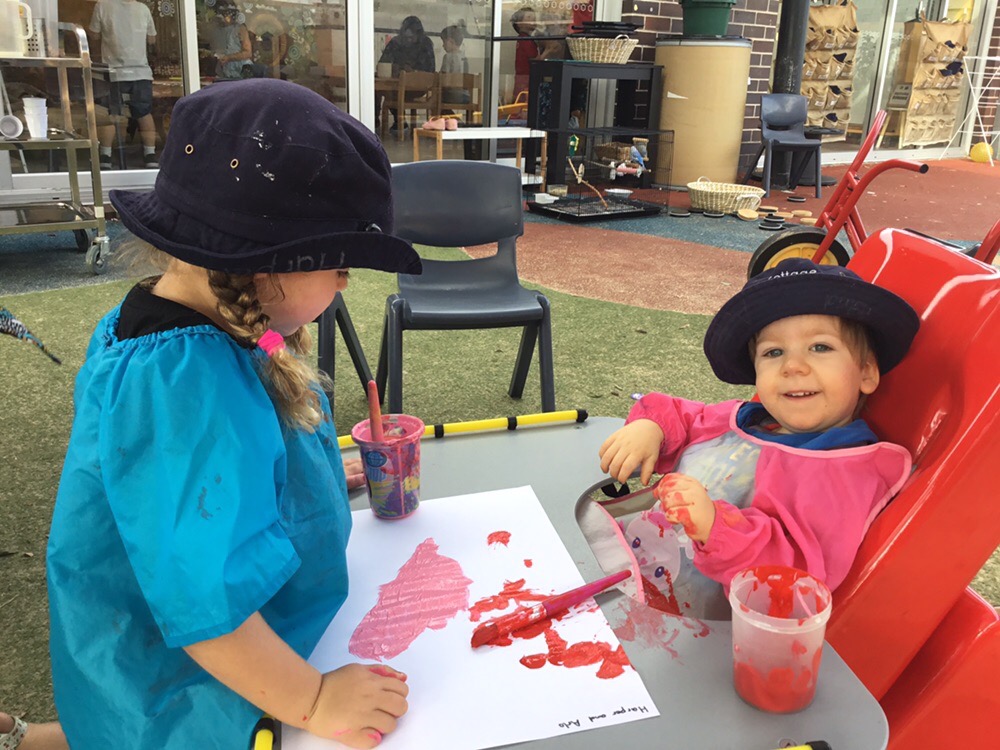 A young boy and girl paint together at an early childhood education setting. 